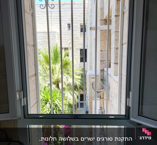חלון עם סורגים לבנים ומסגרת מתכת